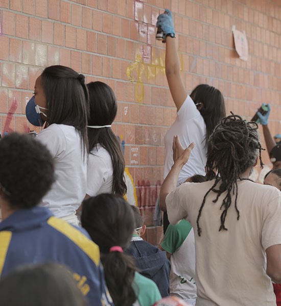 Estudantes grafitando muro de escola